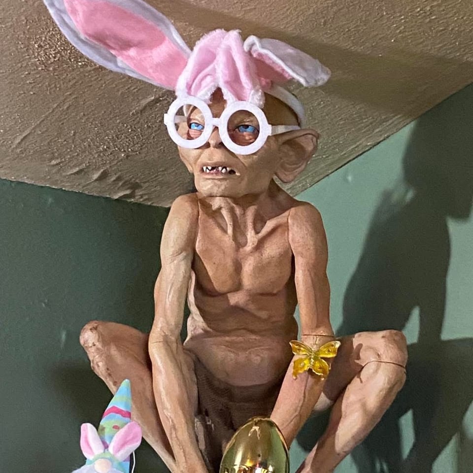 Gollum figurine wearing bunny ears and glasses, with a golden egg and gnome beside it.